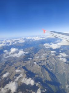 Fotografía hecha desde un avión donde se observan montañas y nubes.
